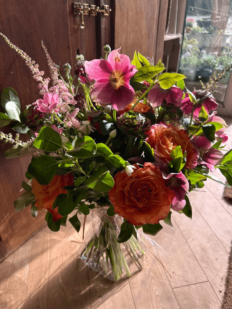 Pastel bouquet arranged with roses, ranunculus and airy foliage.